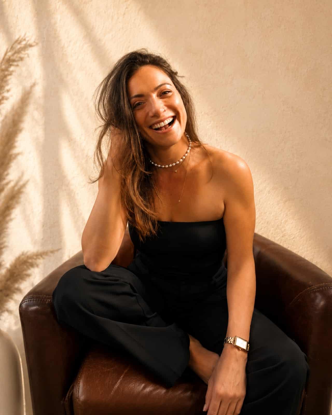Shaena laughing, seated in a leather chair, at ease in her own life