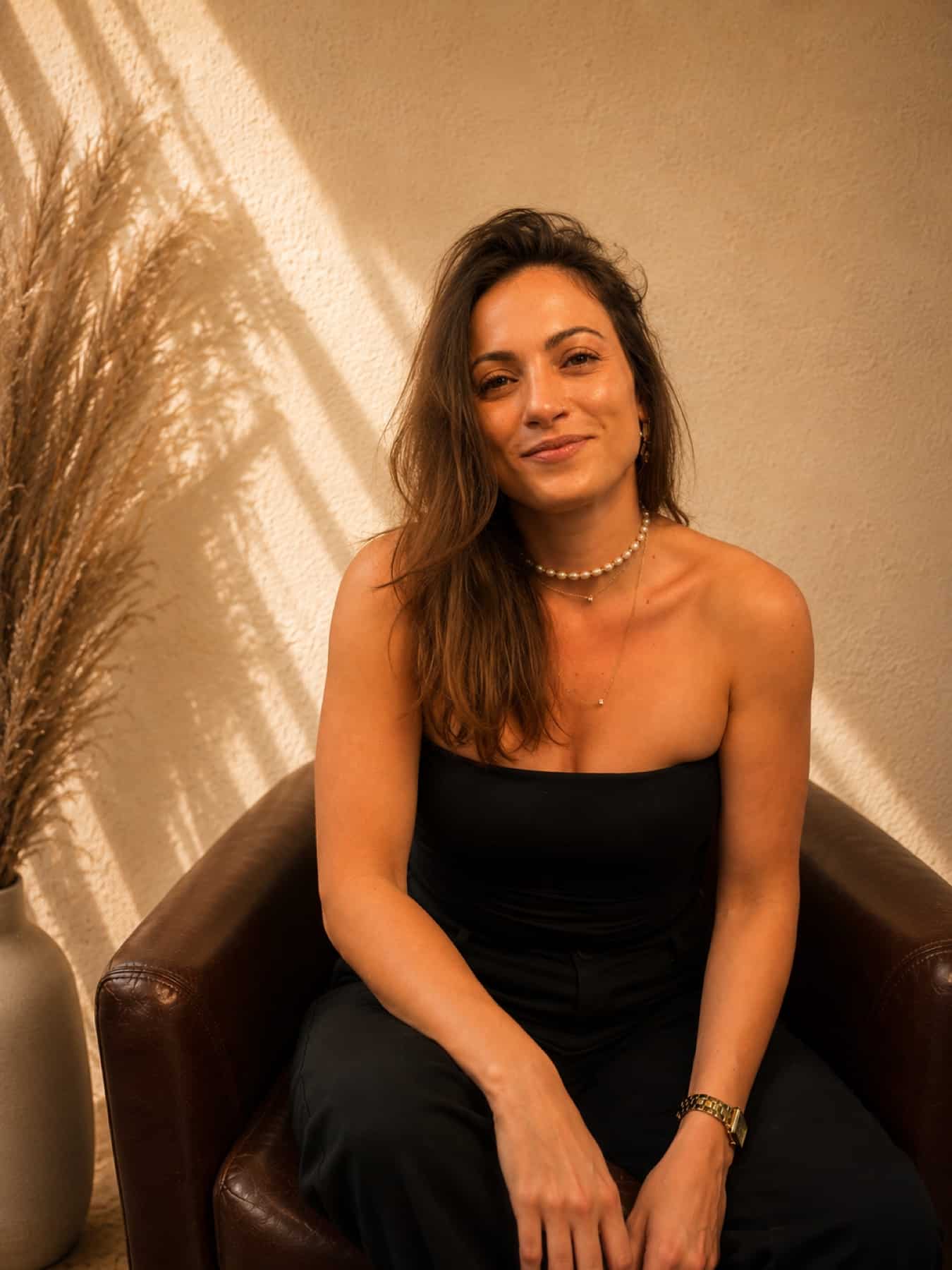 Shaena seated, looking straight at you, in the light where the sessions happen